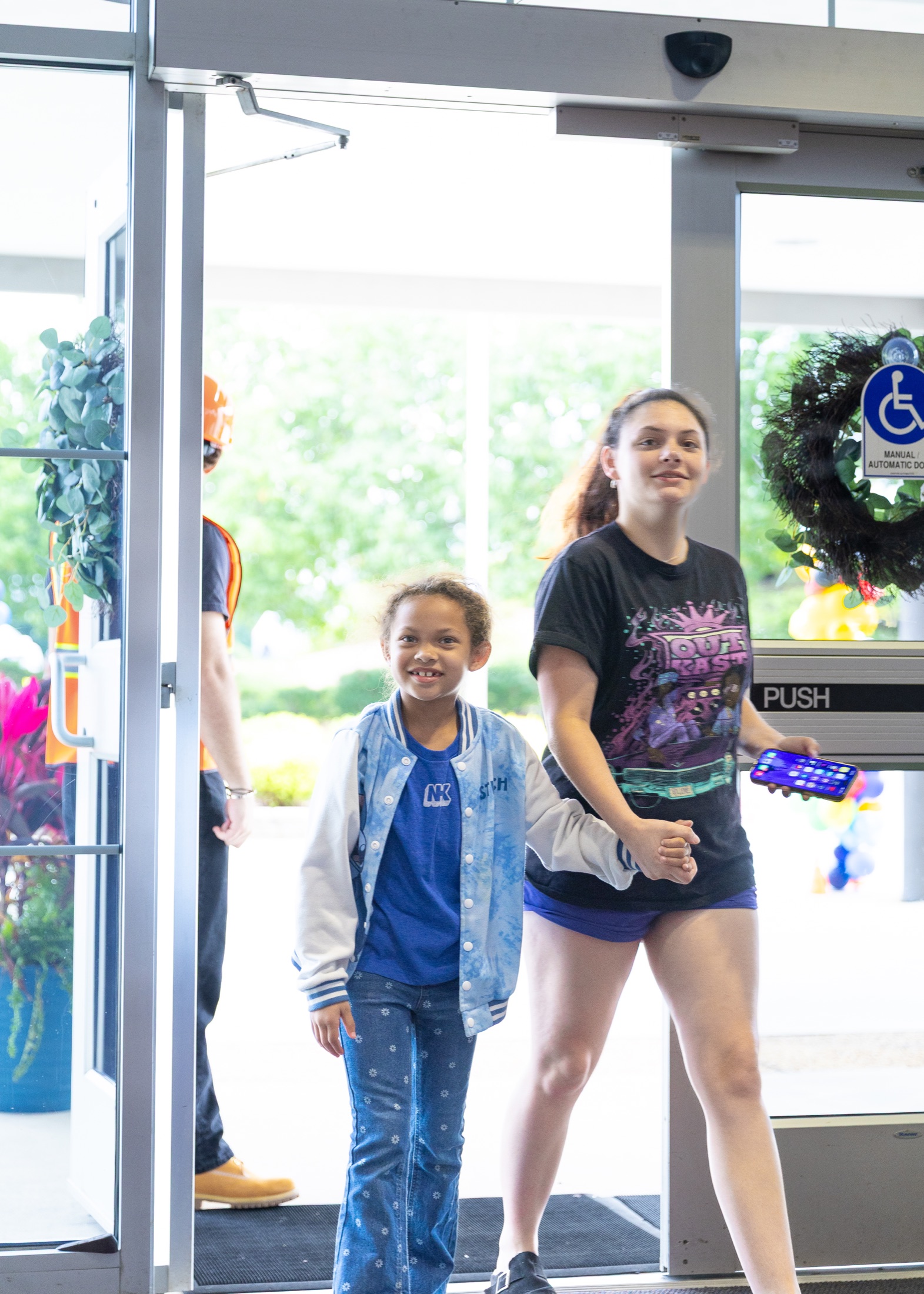 An older student welcoming a younger child through the Kids entrance
